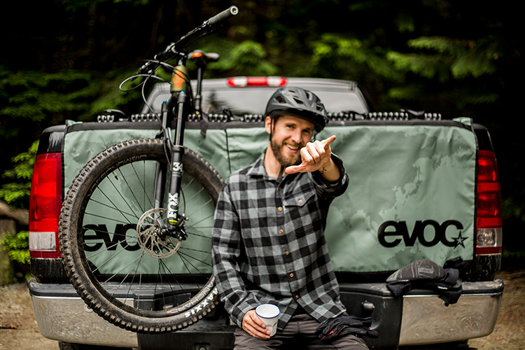 Biker sitting on tailgate with bike loaded in truck