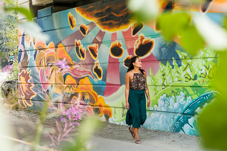 Woman walking by the Chili Thom Mural in Whistler