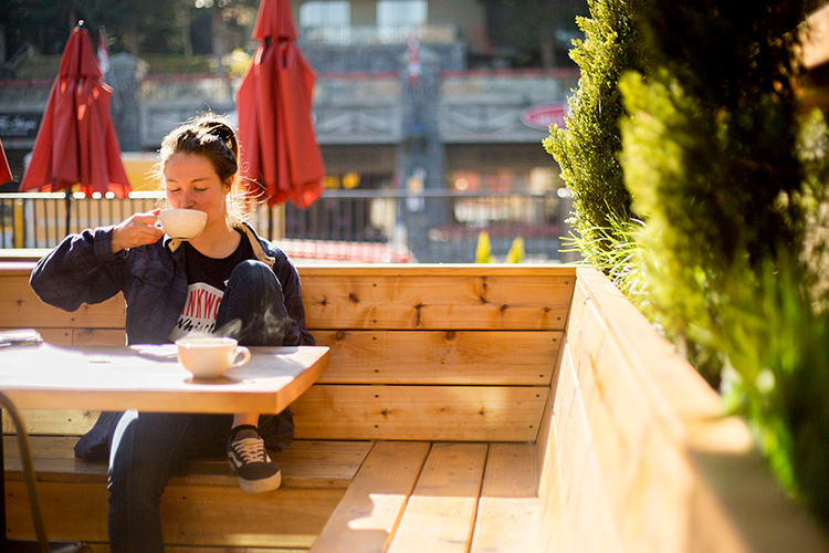 Person on sunny patio drinking coffee in Whistler