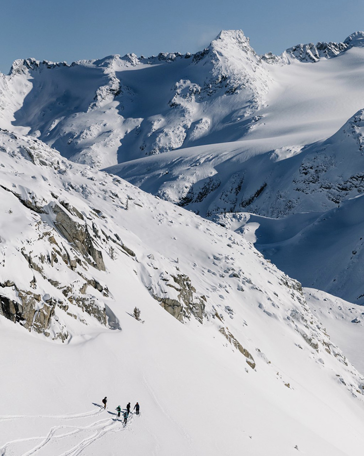 Backcountry skiers below a ridge taking in the views in Whistler