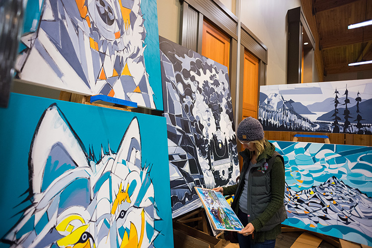 Person looking a big, brigt landscape paintings at the Whistler Artisan Market