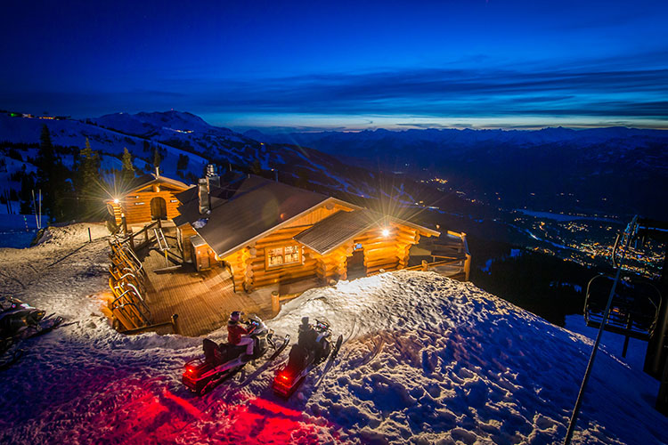 Snowmobilers pull up to the Crystal Hut on Blackcomb Mountain for a fondue dinner.