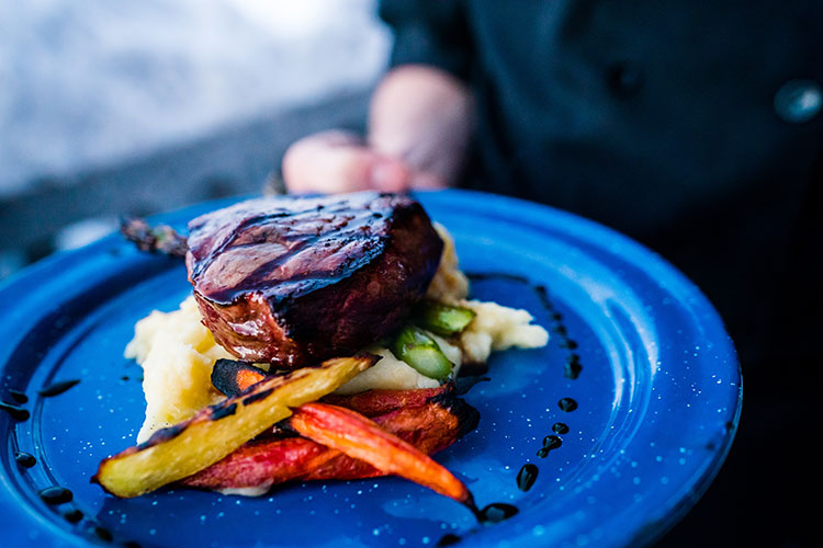 A steak is served at Canadian Wilderness Adventure's snowmobile tour to a backcountry cabin.