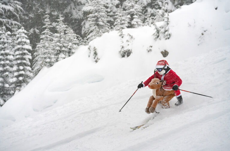 A skier dressed as Santa riding a reindeer charges down the slopes of Whistler Blackcomb.