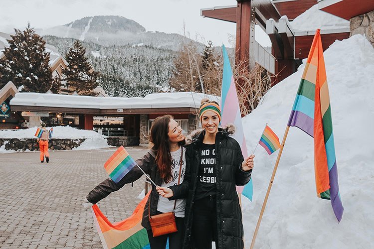 Two women hold rainbow flags at the Whistler Pride and Ski Festival