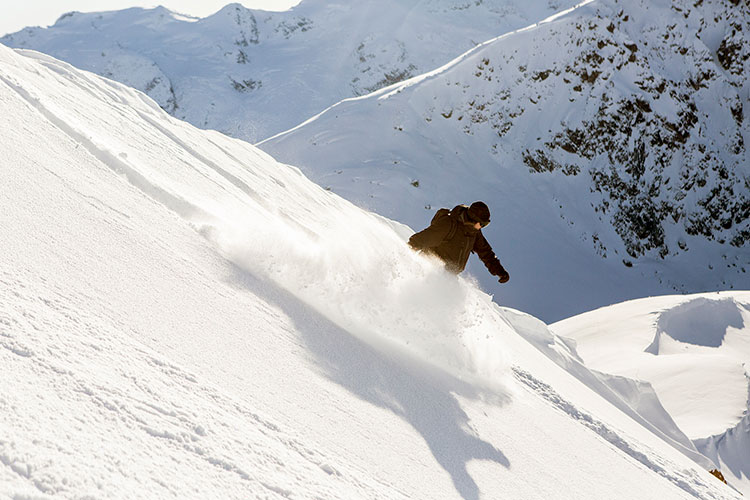 A snowboarder enjoys the powder on a run with Whistler Heli-Skiing