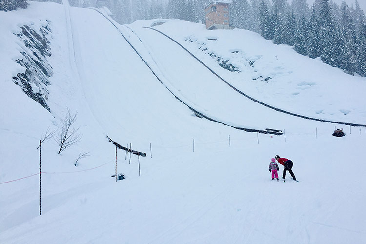 Two cross country skiers look up towards the ski jump at Whistler Olympic Park.