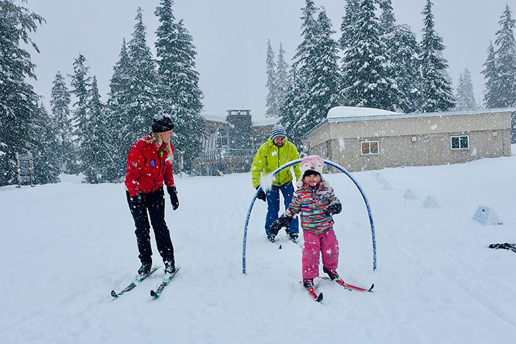 A toddler goes through at hoop while cross country skiing at Whistler Olympic Park.