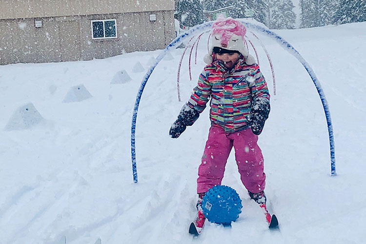 Toddler pushing a ball while cross country skiing in whistler.