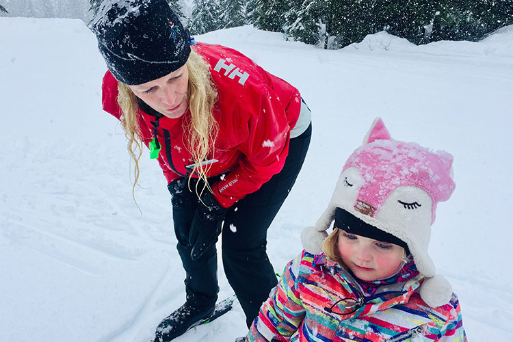 An instructor at Whistler Olympic Park teaching a toddler to cross country ski.