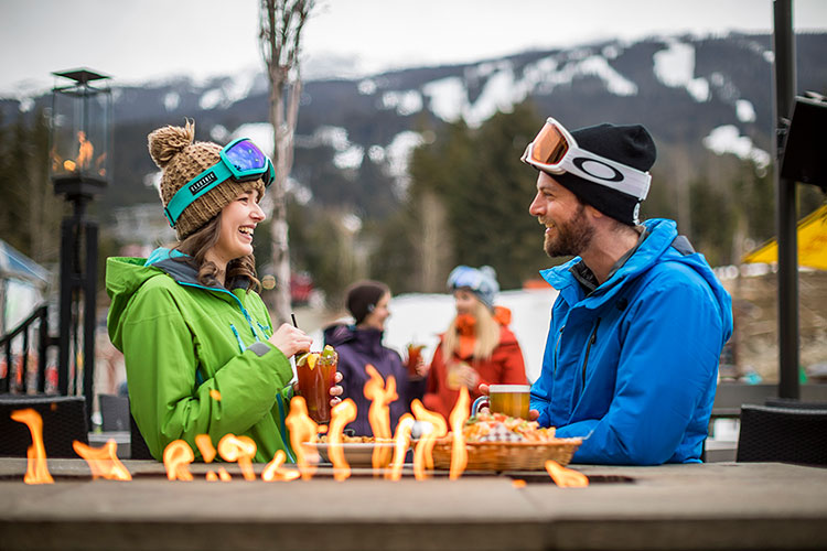 A couple enjoy drinks and food on the Longhorn patio in Whistler