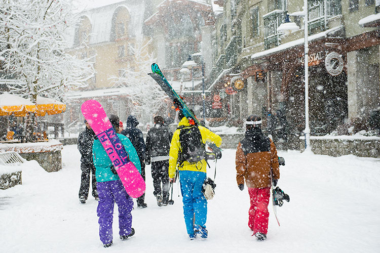 Three friends walk towards the slopes in their ski gear in Whistler.