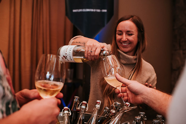 A woman pours cider into glasses at Whistler's Cornucopia festival.