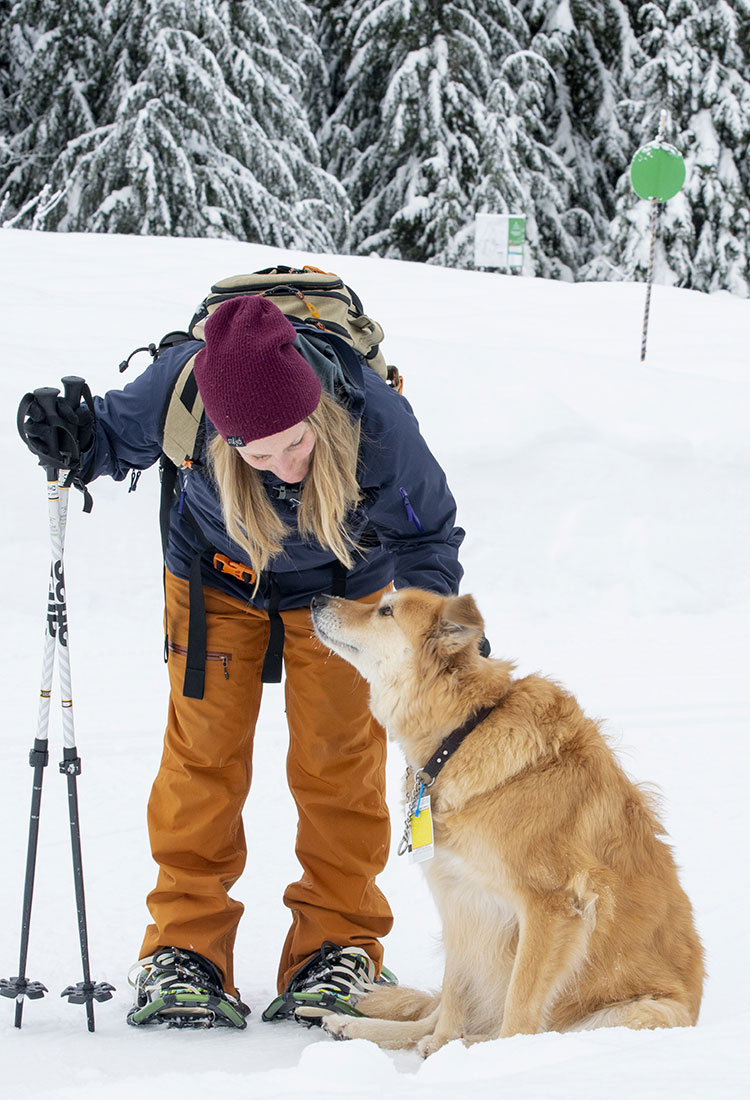 A woman pets her dog after a day spent snowshoeing at Whistler Olympic Park.