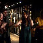 A group of friends laugh as they saber sparkling wine in the wine cellar of the Bearfoot Bistro in Whistler.