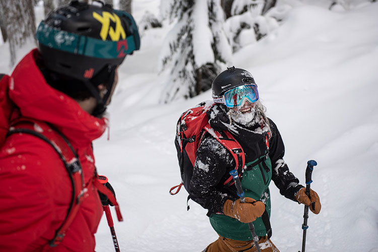 Two skiers stop on a powdery tree run.