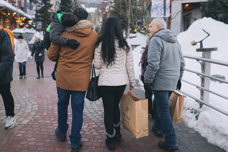 A family walk down the Whistler Village stroll while they shop.