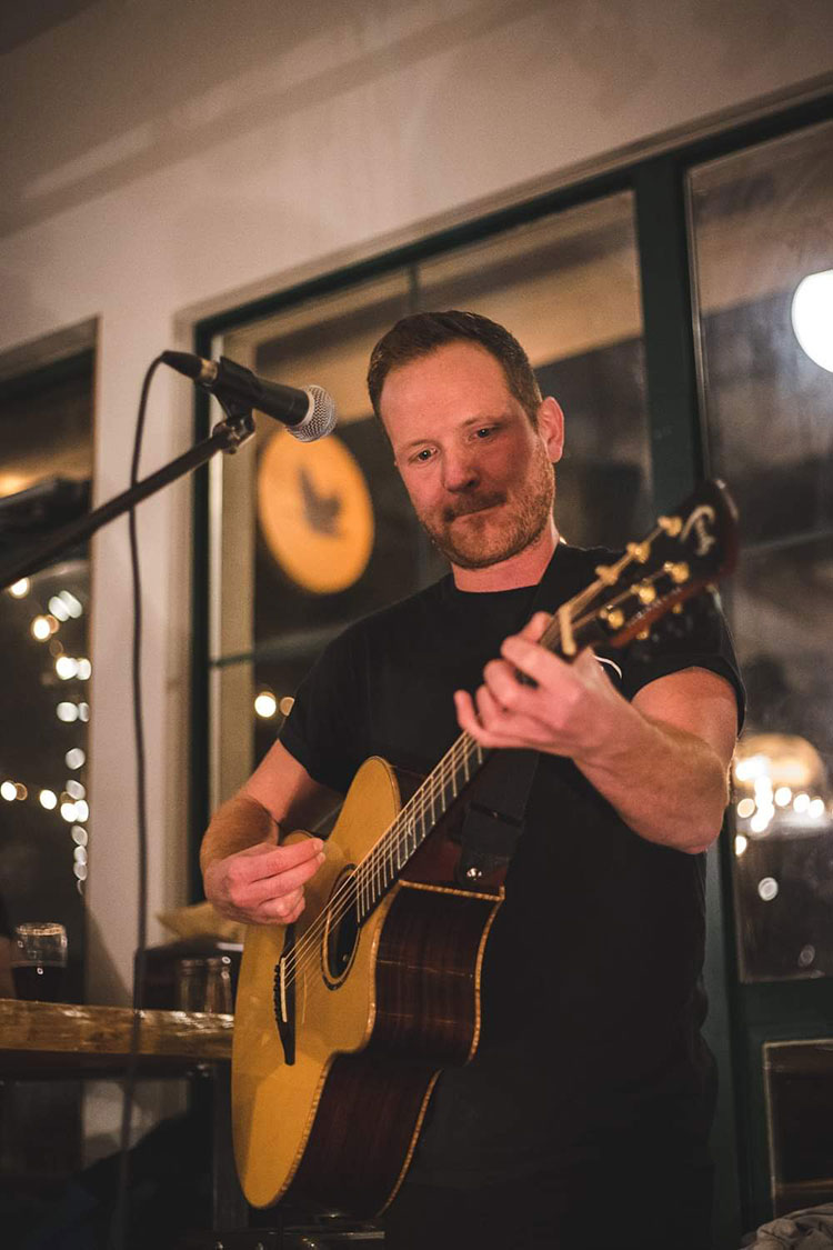 Musician Conor Fitzpatrick playing his guitar on stage in Whistler.