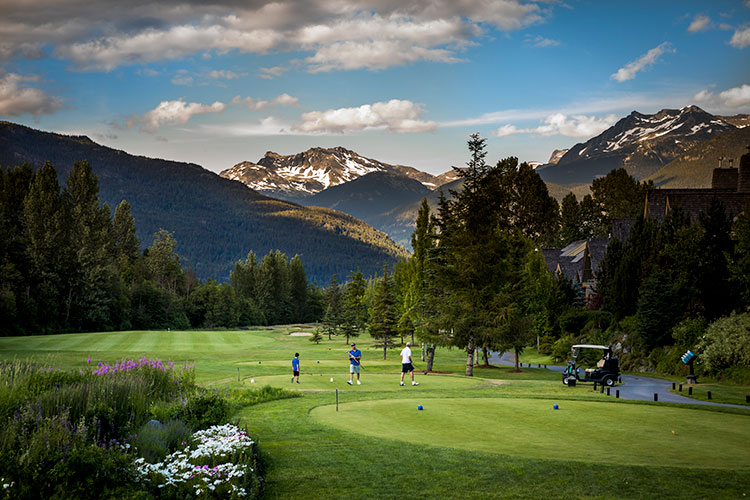 Golfers play on a Whistler golf course in the shadow of the mountains.