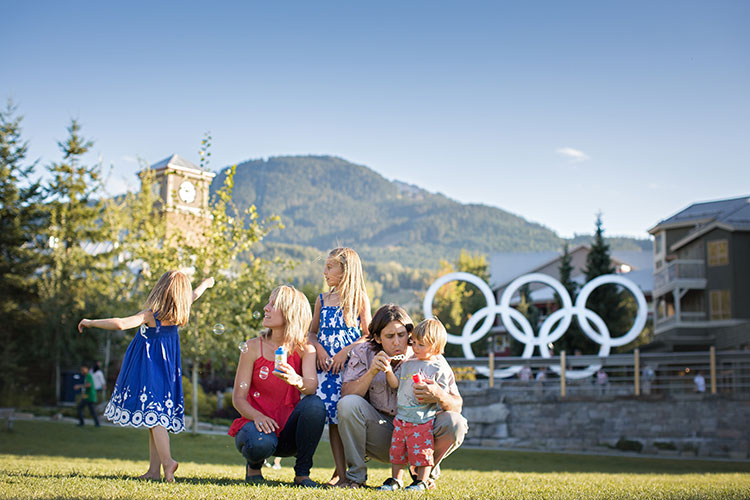 A family blow bubbles on a sunny day in Whistler Olympic Plaza.