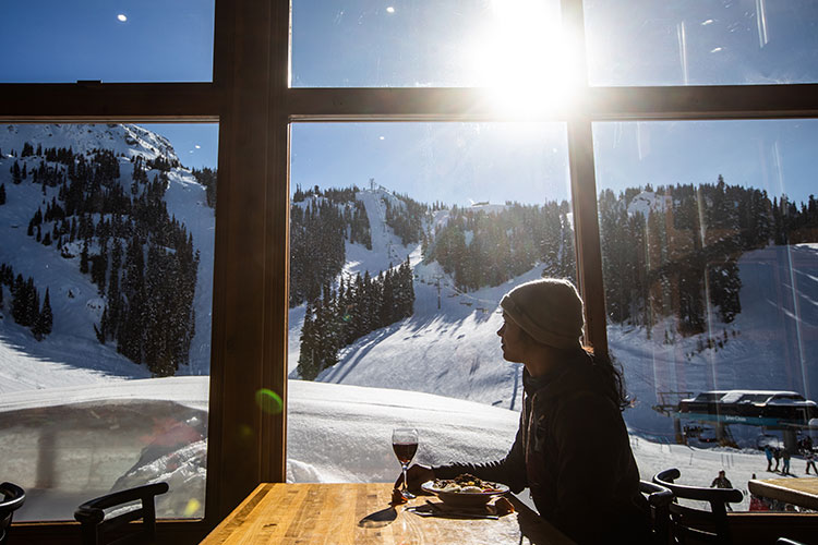 A woman enjoys the mountain views over lunch at Whistler Blackcomb.