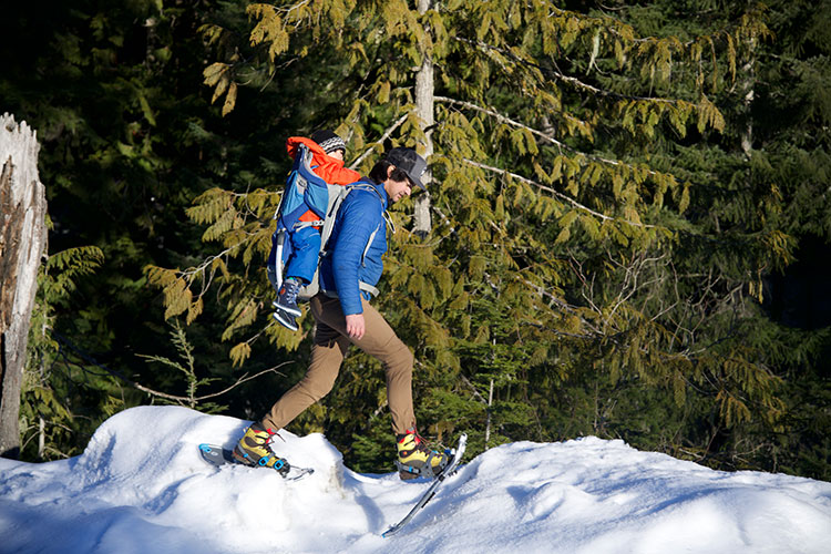 A father carries his son in a backpack as he snowshoes at Whistler Olympic Park.