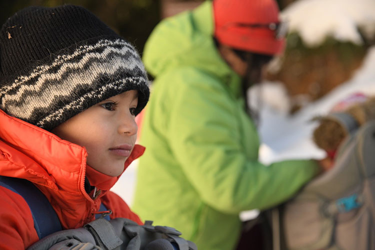 A toddler waits in a backpack to go on a snowshoe trip in Whistler.