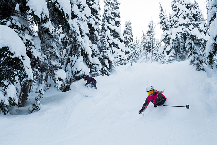 A skier and snowboarder rip down Raptor's Ridge on Whistler Blackcomb.