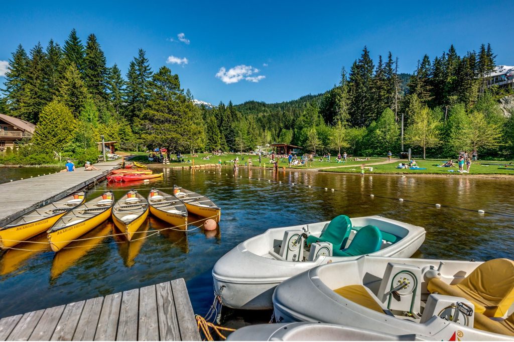 Canoes and pedal boats attached to the wooden dock on Alta Lake at Lakeside Park in Whistler.