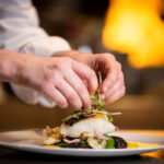 A chef puts the final touches to a plate for the Spring Culinary Series by Cornucopia.