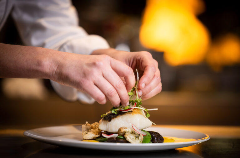 A chef puts the final touches to a plate for the Spring Culinary Series by Cornucopia.