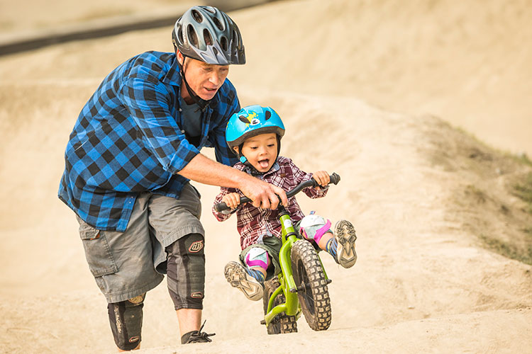 A man teaches a young child to bike ride in Whistler.