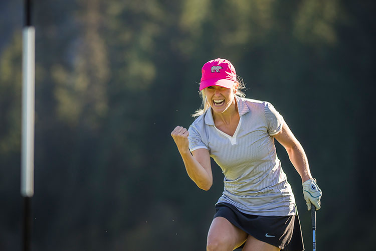 A woman pumps her fist after a hole in one on a golf course in Whistler.