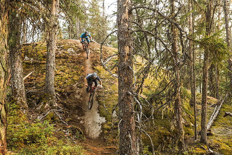 Two mountain bike riders come down a steep rock face in Whistler.