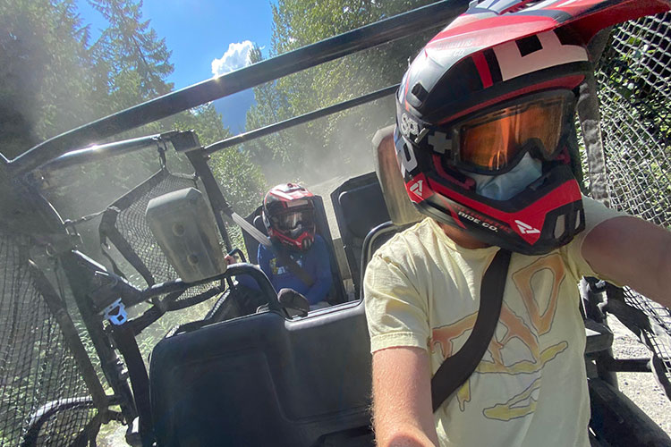 A father takes the wheel of an off-road mountain buggy with his son in the back.