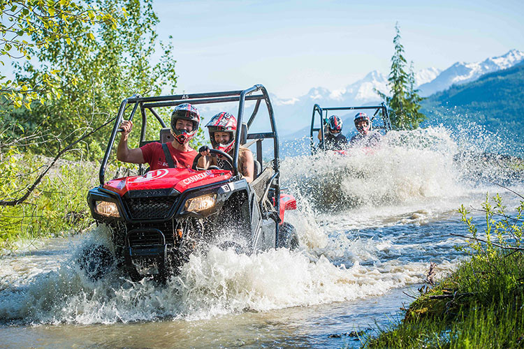 Two mountain buggies splash through water in Whistler.