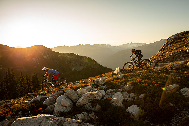 Two mountain bike riders comes down the trail as the sun sets in Whistler.