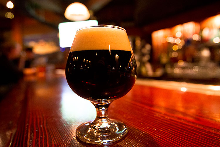 A dark ale sits on a wooden bar at The Brewhouse in Whistler.