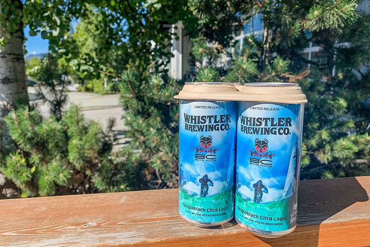 A six pack of Whistler Brewing Company lager on a bench in the sunshine.