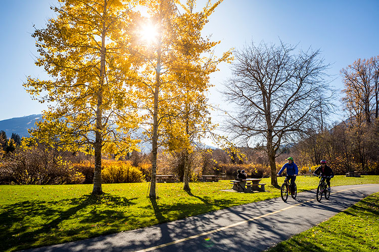 Two people ride bikes along Whistler's Valley Trail in the fall. 