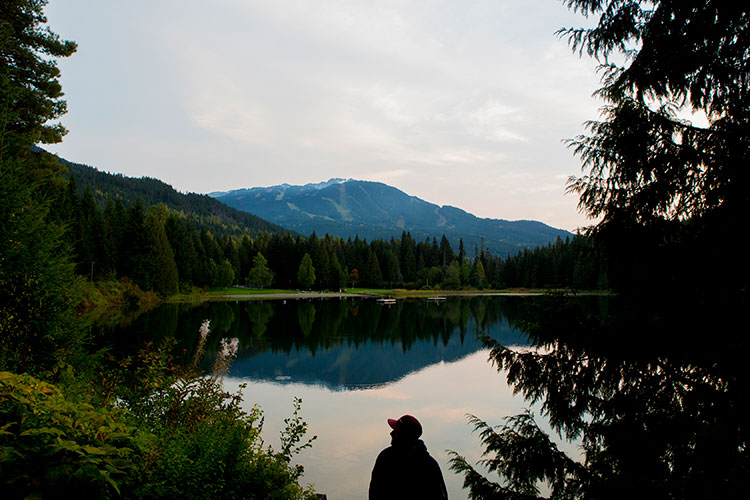 A man looks out over Lost Lake at the mountains in the background.