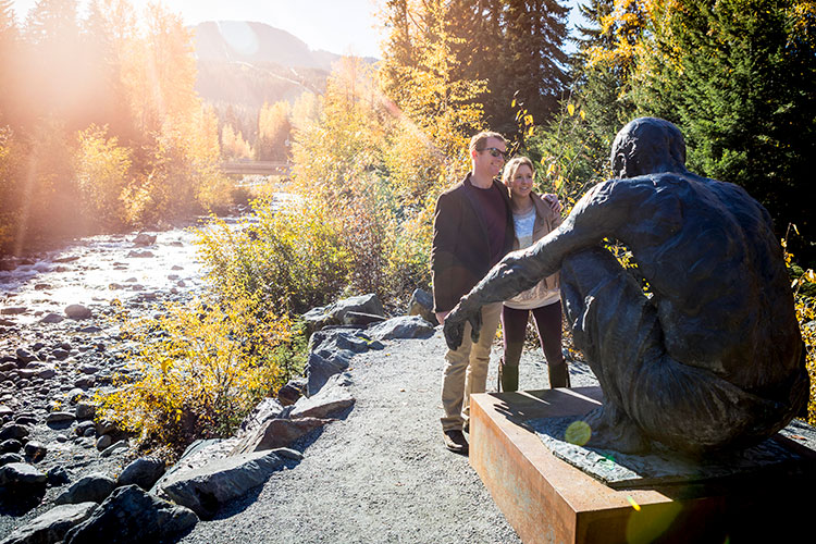 A couple look at public art in Whistler in the fall. 