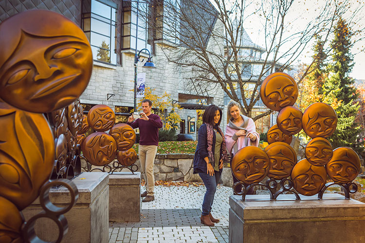 People admire the Timeless Circle sculpture in the beauty of fall in Whistler.