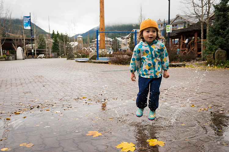 A child splashes in a puddle along Whistler's Village Stroll in the fall.