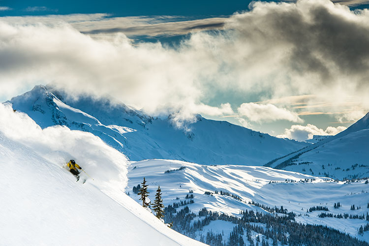 A skier sends it down a steep slope through powdery snow on Whistler Blackcomb.