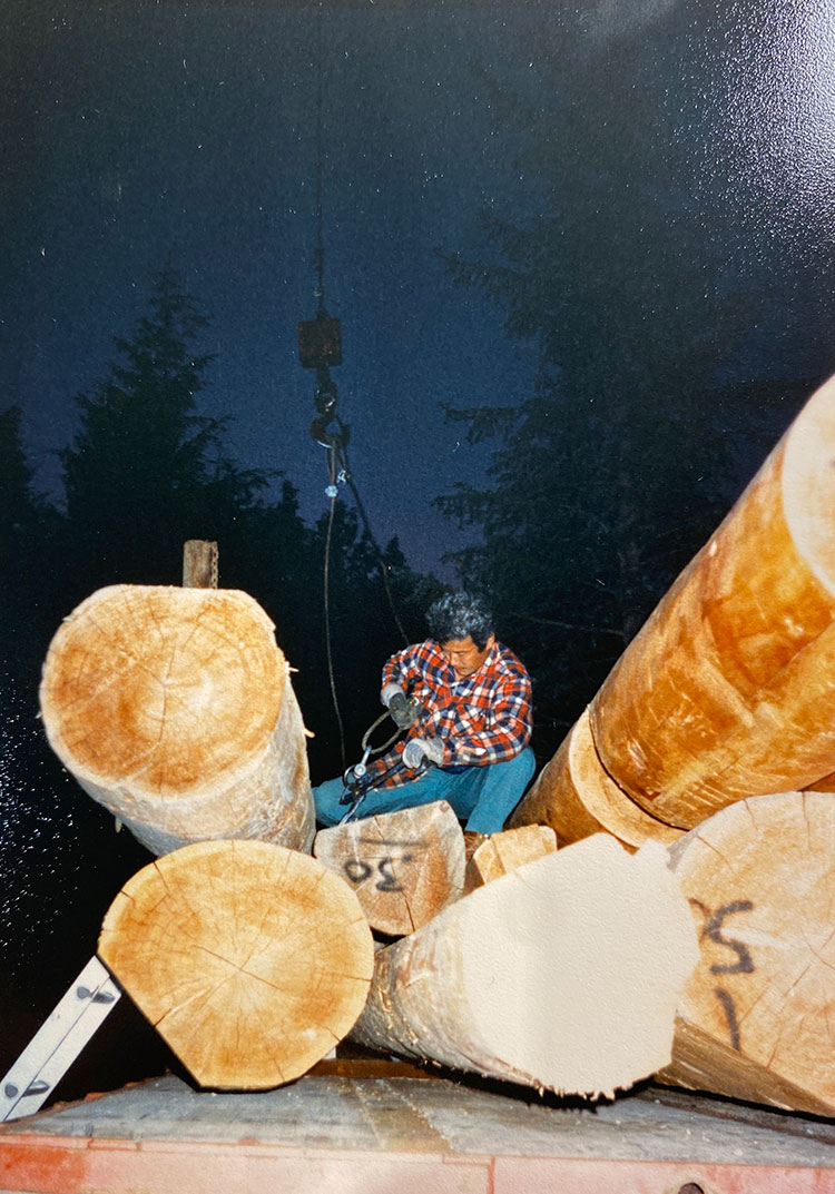 Toshi Hamazaki sits on huge logs that he will use to build his home in Whistler.