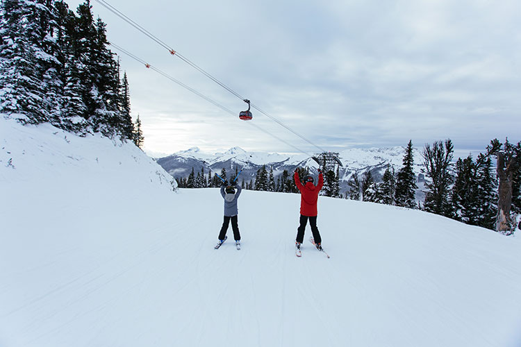 Father and son skiers raise their arms celebrating their first day on the slopes for this season.