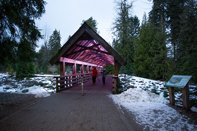 Two skiers walk across the covered bridge that connects the Village and Upper Village in Whistler. 