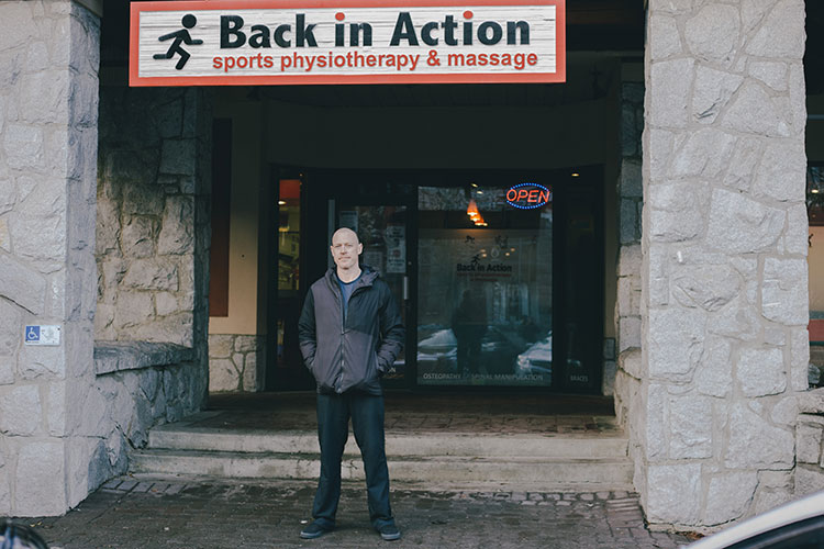 Mike Conway stands below his business sign, Back In Action, in Whistler.