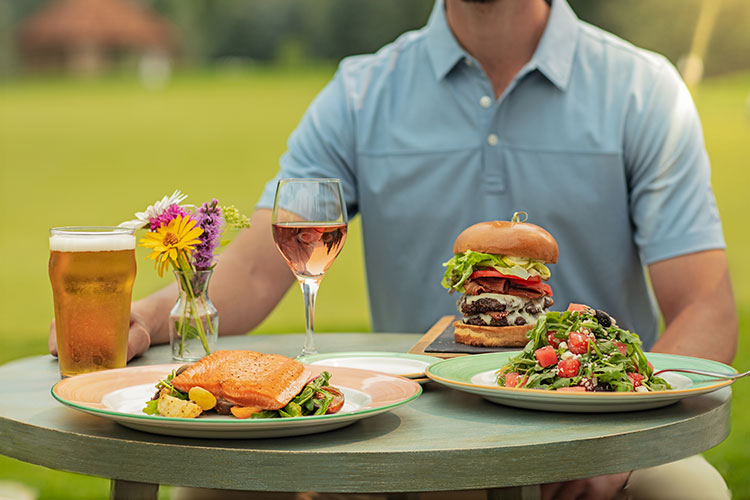 A summery table at the Fairmont Chateau Whistler Golf Course with salmon, salad and their famous Chip Out Burger.